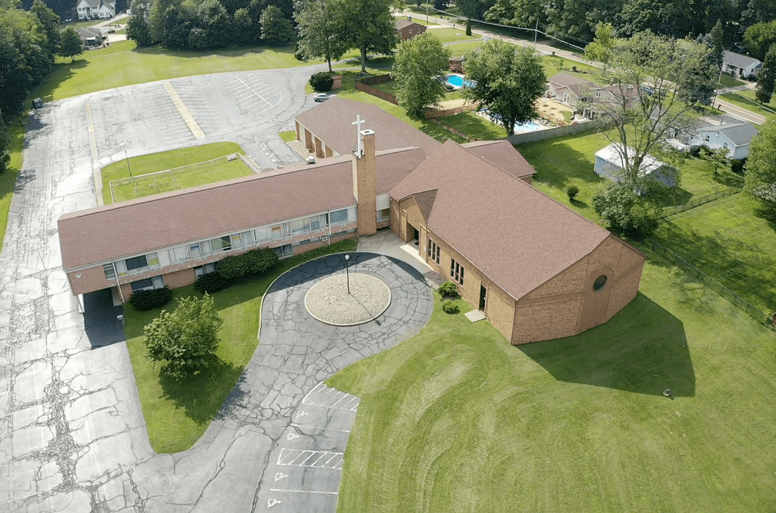 An aerial view of a church with a parking lot in the background.